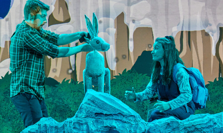 Two performers on stage holding a puppet rabbit