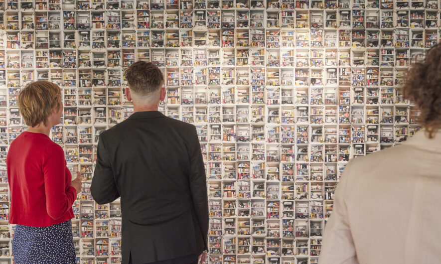 Two people looking at a wall of artwork