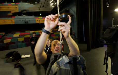 Technician leaning up to put tape over a piece of rope.