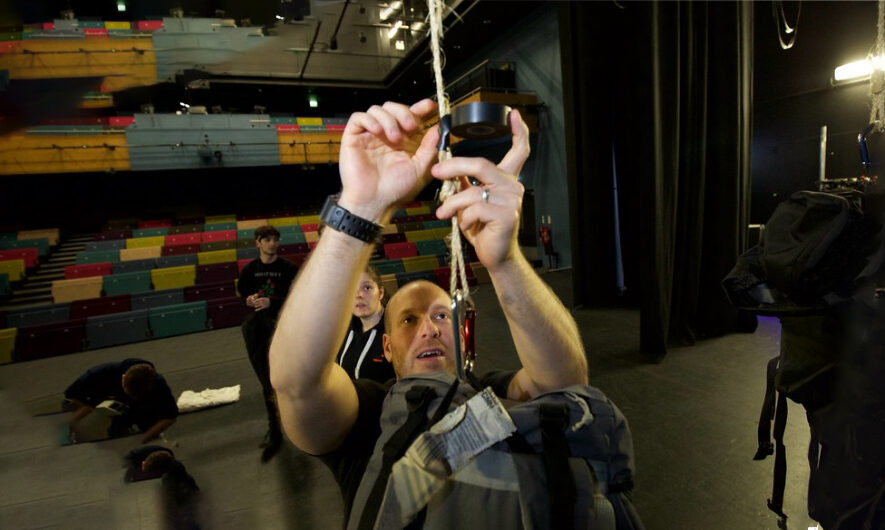 Technician leaning up to put tape over a piece of rope.