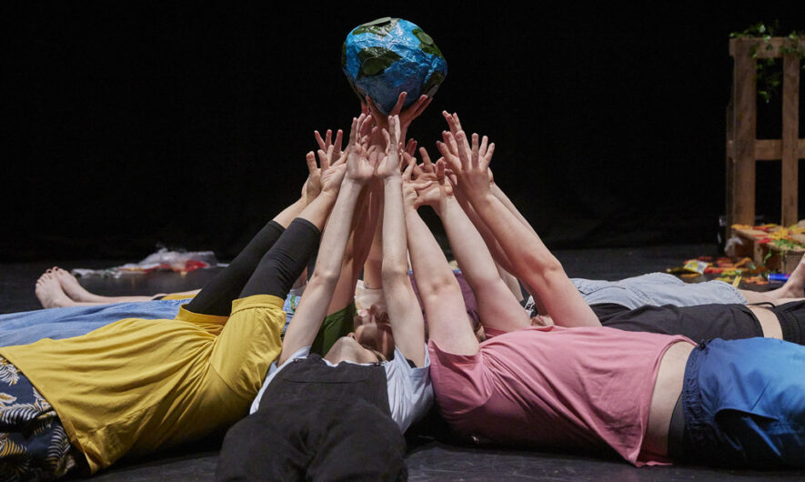 Group of people laying on the floor holding a globe.