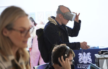 A person uses a VR headset during a student showcase.