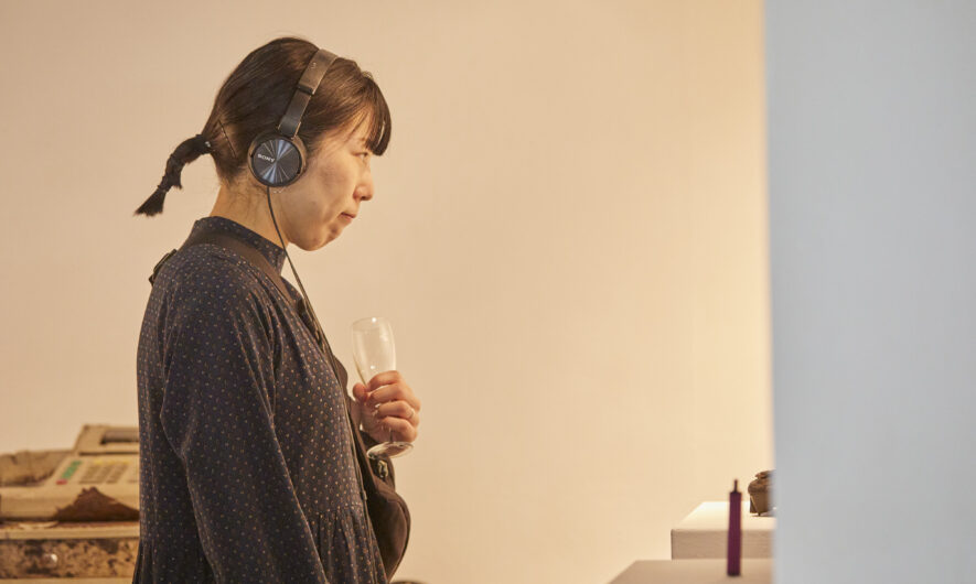 Person holding a drink looking at artwork with headphones on.