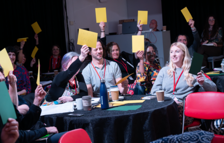 People around a table hold up yellow cards.