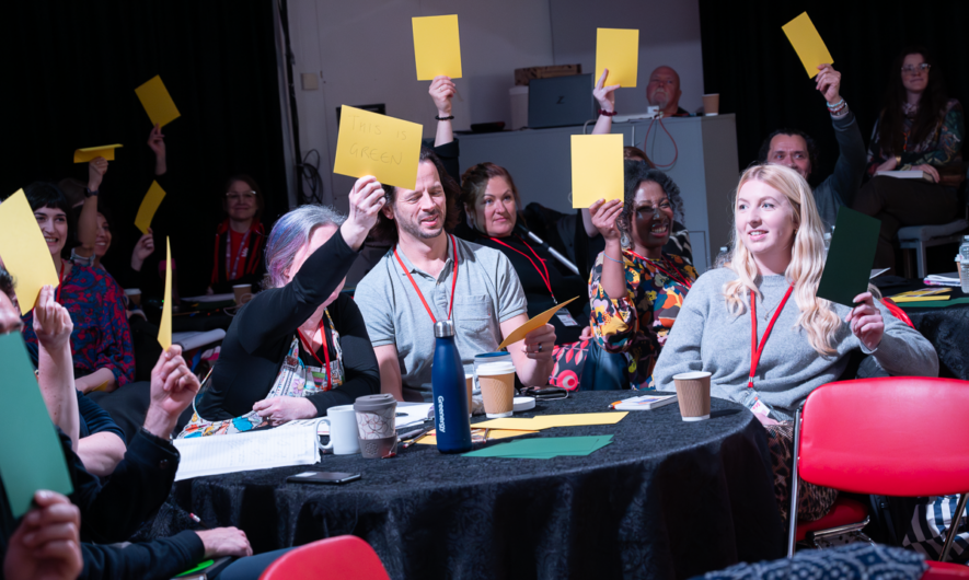 People around a table hold up yellow cards.