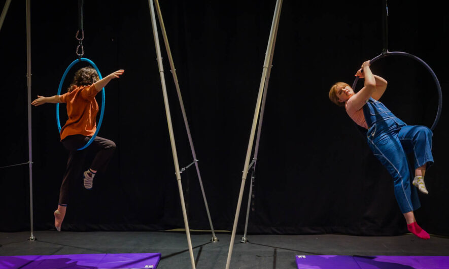 Two people use aerial hoops