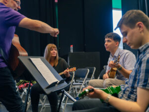 People in a class learning to play ukelele.
