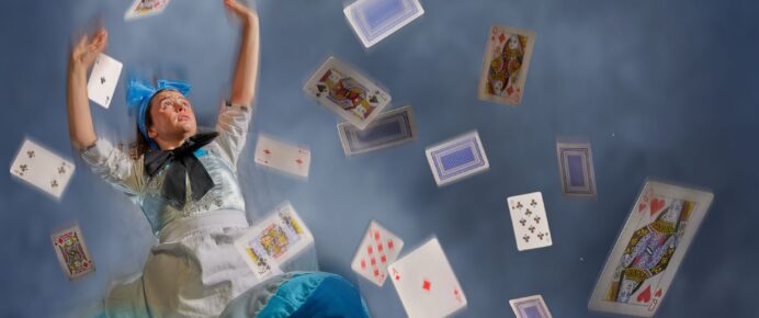 Alice is falling through a blue smokey background, several playing cards fall with her of various suits and numbers.