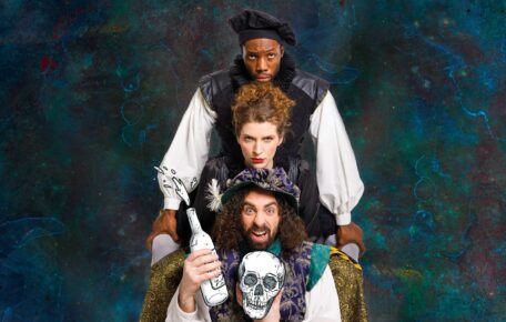 3 performers stand with their chins resting on the others head. The bottom performer rests their head on a drawn skull, and is holding a drawn liquor bottle that is splashing.