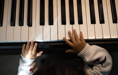 A babies hands are on piano keys.