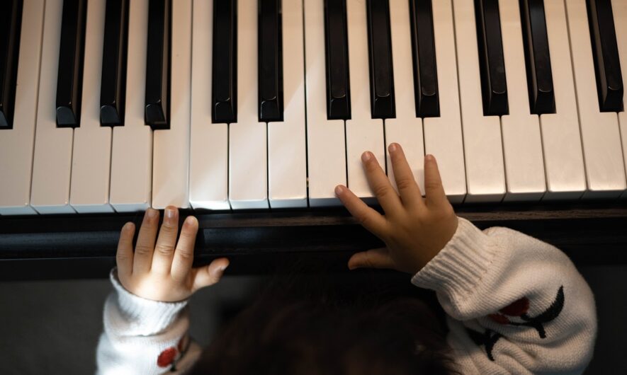 A babies hands are on piano keys.