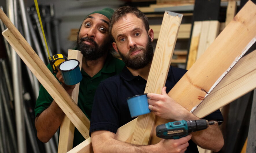 Two men holding wooden planks and mugs.
