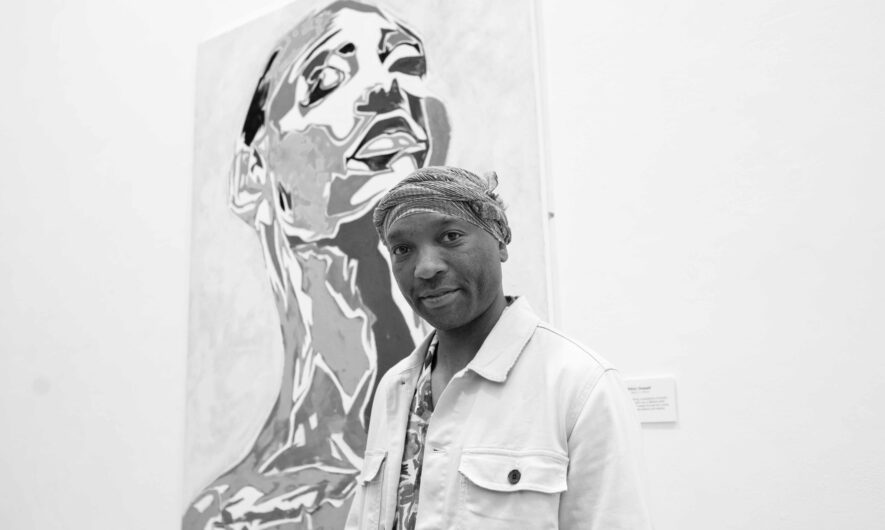 Black and white photo of Tinashe in front of one of his paintings in the gallery.