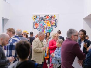 A crowd of people in the gallery around Tinashe's painting.