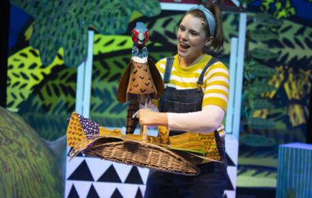 Barmpot Theatre on stage with a bird puppet, the performers mouth is open with excitement as they look at the bird.