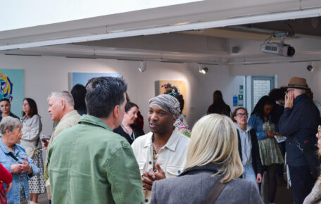 Tinashe Chipawe during opening night of his exhibition 'Community Resilience' surrounded by a crowd taking in his artwork