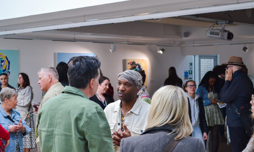 Tinashe Chipawe during opening night of his exhibition 'Community Resilience' surrounded by a crowd taking in his artwork