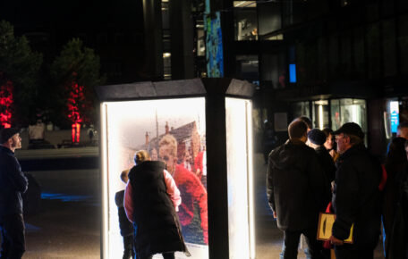 Group of people gather around the art installation The Lincolnshire Mosaic of freedom.